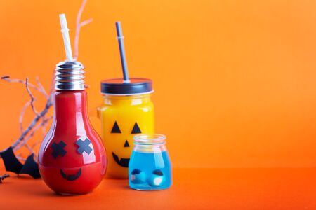 Halloween healthy pumpkin and tomato juices in the glass jar on a orange background with copy spaceの写真素材