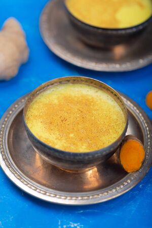 Golden turmeric milk on the blue  with ingredientsの写真素材