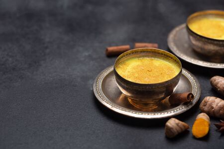 Golden turmeric milk on the black  with ingredientsの写真素材