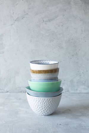 Clean dishes on the table in a stack on a gray background, vertical orientation, natural lightの写真素材