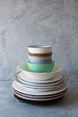 Clean dishes on the table in a stack on a gray background, vertical orientation, natural lightの写真素材