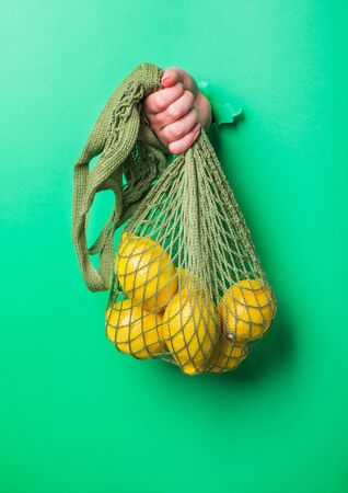 A woman holds reusable Cotton String Portable Shopping Handbag with lemonsの写真素材