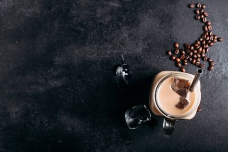 Glass vintage jar of coffee with milk on a dark