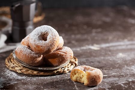 Donuts with falling icing sugar on dark background with copy space