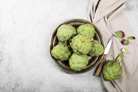 Pile of green Spanish or Italian Artichokes on the metal rustic plate and gray background. Top view with copy spaceの写真素材