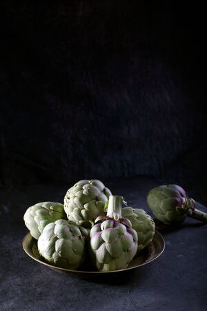 Pile of green Spanish or Italian Artichokes on the metal rustic plate with copy spaceの写真素材