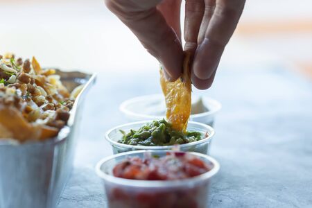 A man dips nachos in green guacamole sauce.の写真素材