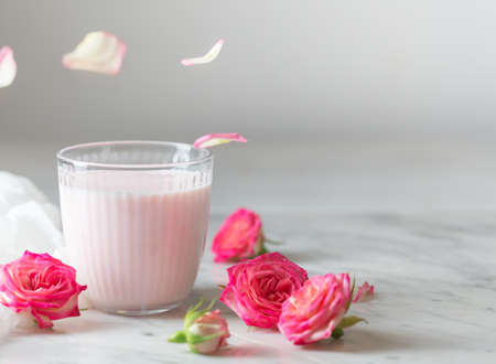 Rose moon milk with flying petals for a better sleep. Ayurveda warm drink consumed before bed. Nice in case of sleeplessness, anxiety and insomnia. Copy spaceの写真素材