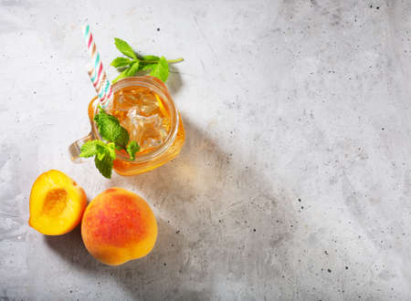 Peach ice tea on concrete gray background with mint and iceの写真素材
