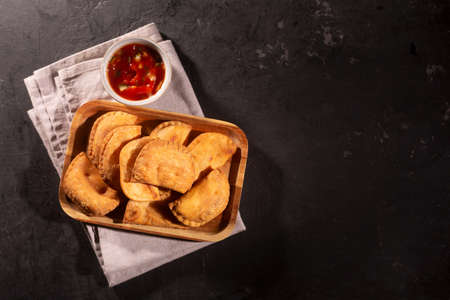 Typical Colombian empanadas usually served with spicy sauce on black background and copy space