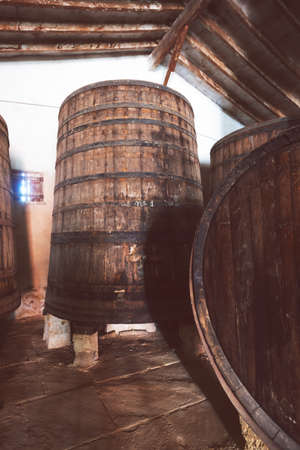 Red wine barrels stacked in the old cellar of the vinery in Spain, Alicante. Toned photo