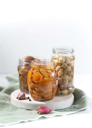 Glass jar with canned mushrooms with garlic and pepper. Fermented food on a white background