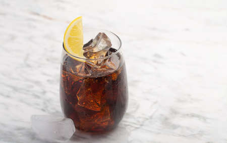 Glass of cola with ice and lemon on the white background with copy spaceの写真素材