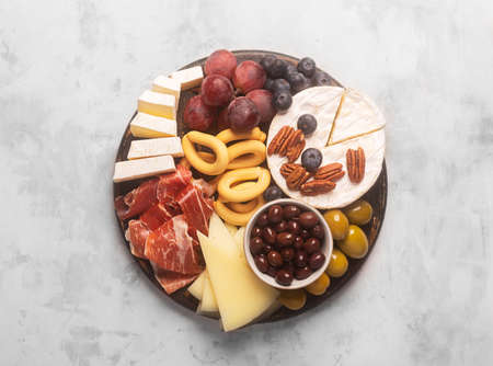 Charcuterie board with spanish jamon, pork sausage with pepper, fuet, cheese and berries on a gray...