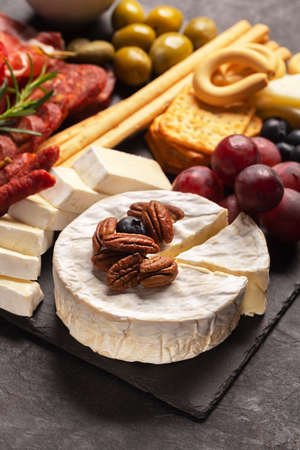Charcuterie board with Camembert, fuet, nuts cheese and berries on a dark backgroundの写真素材