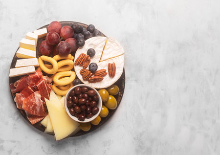 Charcuterie board with spanish jamon, pork sausage with pepper, fuet, cheese and berries on a gray concrete backgroundの写真素材