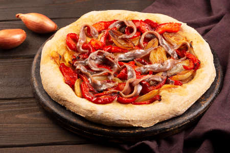 Spanish coca with onion, bell pepper and anchovy on a dark wooden background. Traditional vegetarian pizza or tarte in Spainの写真素材