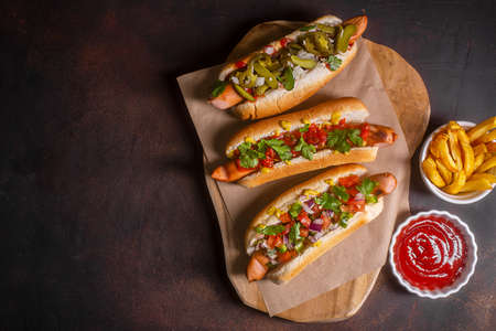 Hot dogs with different spicy toppings, dark background with copy space, horizontalの写真素材