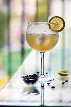 Cold alcoholic cocktail cuba libre in a misted glass with lemon and coffee beans on the edge of the table in a cafe. Summer cafeの写真素材