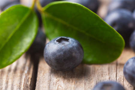 Organic blueberry close-up with leaves and berries scattered on a wooden background. Selective focusの写真素材