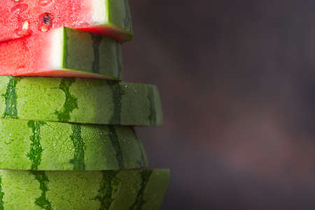 Red raw watermelon pieces on dark background close up with copy space. It sweet, juicy flesh, usually deep red to pink, with many seedsの写真素材