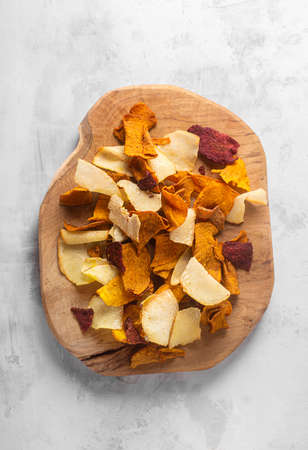 Vegetable chips close-up of potatoes, beets, carrots on a wooden board top viewの写真素材