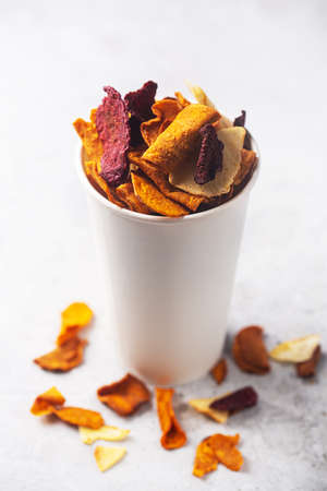 Vegetable organic potato, beet and carrot chips in a white snack glassの写真素材