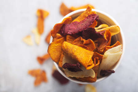 Vegetable organic chips made from potatoes, beets and carrots in a white glass for a snack, top viewの写真素材