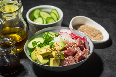 Traditional Hawaiian Poke Bowl prepared with Tuna Fish, rice and vegetables, dark and moody photo