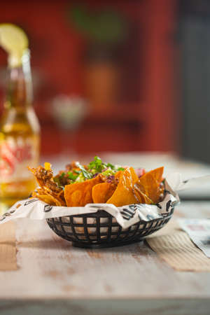 Mexican snack nachos with guacamole and pico de gallo sauce on the table in a mexican restaurant. Also bottle of beer on the tableの写真素材