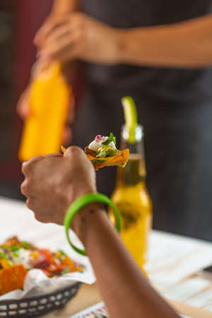 Restaurant visitors eating mexican snack nachos with guacamole and pico de gallo sauceの写真素材