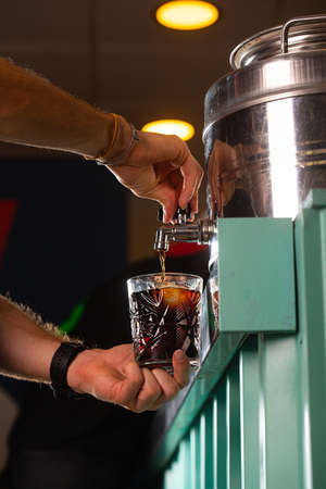 Barman pouring a vermut from a barrel into a glass in a bar