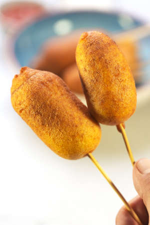 Man holds Corn two corn dogs cooked with sausage and wheat dough with the addition of corn flour