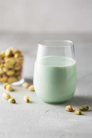 Pistachio milk in the bottle surrounded by pistachios on the green background, top view. This milk is a great source of antioxidants, phytosterolsの写真素材