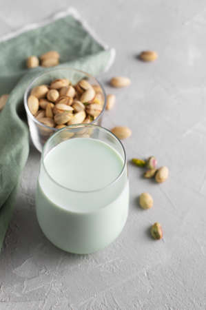 Pistachio milk in the bottle surrounded by pistachios on the green background, top view. This milk is a great source of antioxidants, phytosterolsの写真素材