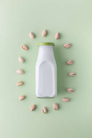 Pistachio milk in the bottle surrounded by pistachios on the green background, top view. This milk is a great source of antioxidants, phytosterolsの写真素材