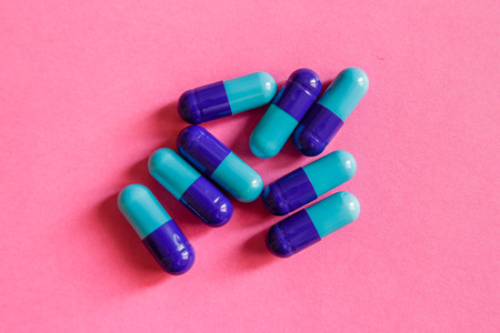 A pile of blue-purple capsules on pink background, close upの写真素材