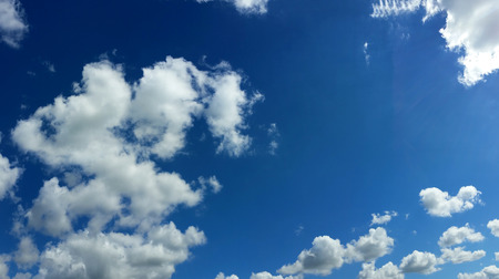 View from bottom on the white clouds on the blue sky background.