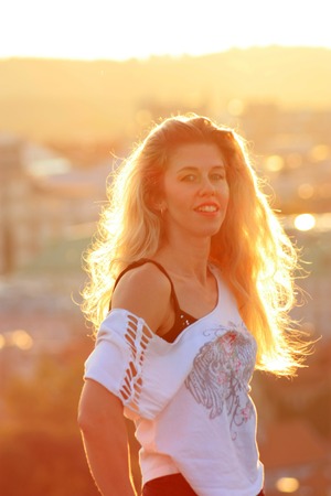 smiling blonde girl in the sunlight, cityscape background.の写真素材