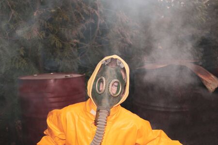 portrait of a human in a gas mask and a protective yellow suit. Background -rubbish dump.の写真素材