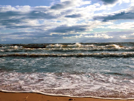 Autumn storm on the Baltic Sea. Waves run into the sandy beach. Gray clouds over storm waves.の写真素材