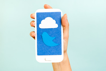 Conceptual phone showing a cloud and bird on blue backgroundの写真素材