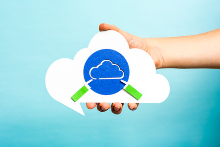Hand holding cloud speech bubble with blue cloud. Internet concept.の写真素材