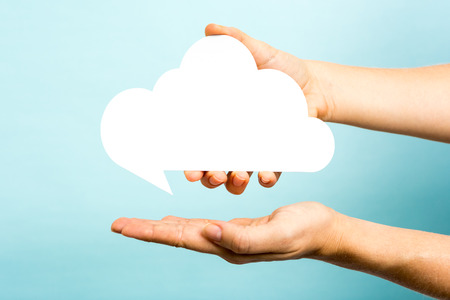 one hand showing a white cloud on blue background. の写真素材