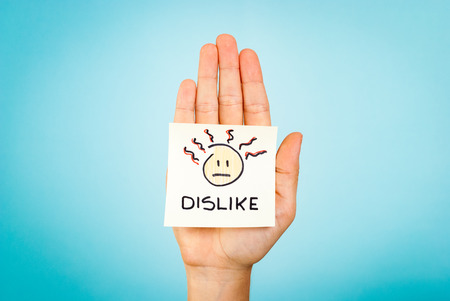 Dislike emoticon note on hand with blue background
