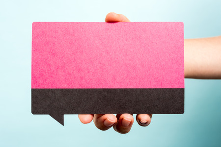 Hand holding female pink speech bubble on blue background. の写真素材