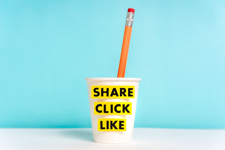 Social media concept. Cup paper with pencils and words share click like on blue background