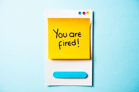 YOU'RE FIRED text with paper smart phone concept on blue background. Paper card with illustration.の写真素材