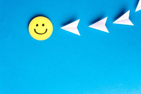 Yellow happy smiling face with paper airplanes on blue background. Social media, send and sharing concept. Content marketing concept.の写真素材