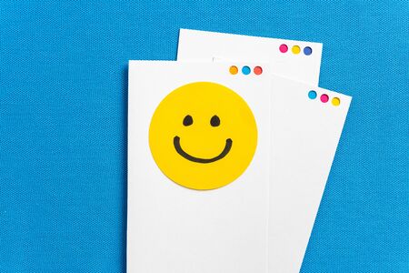 Notes with yellow circle happy smiling face cartoon on paper screen card and blue texture...